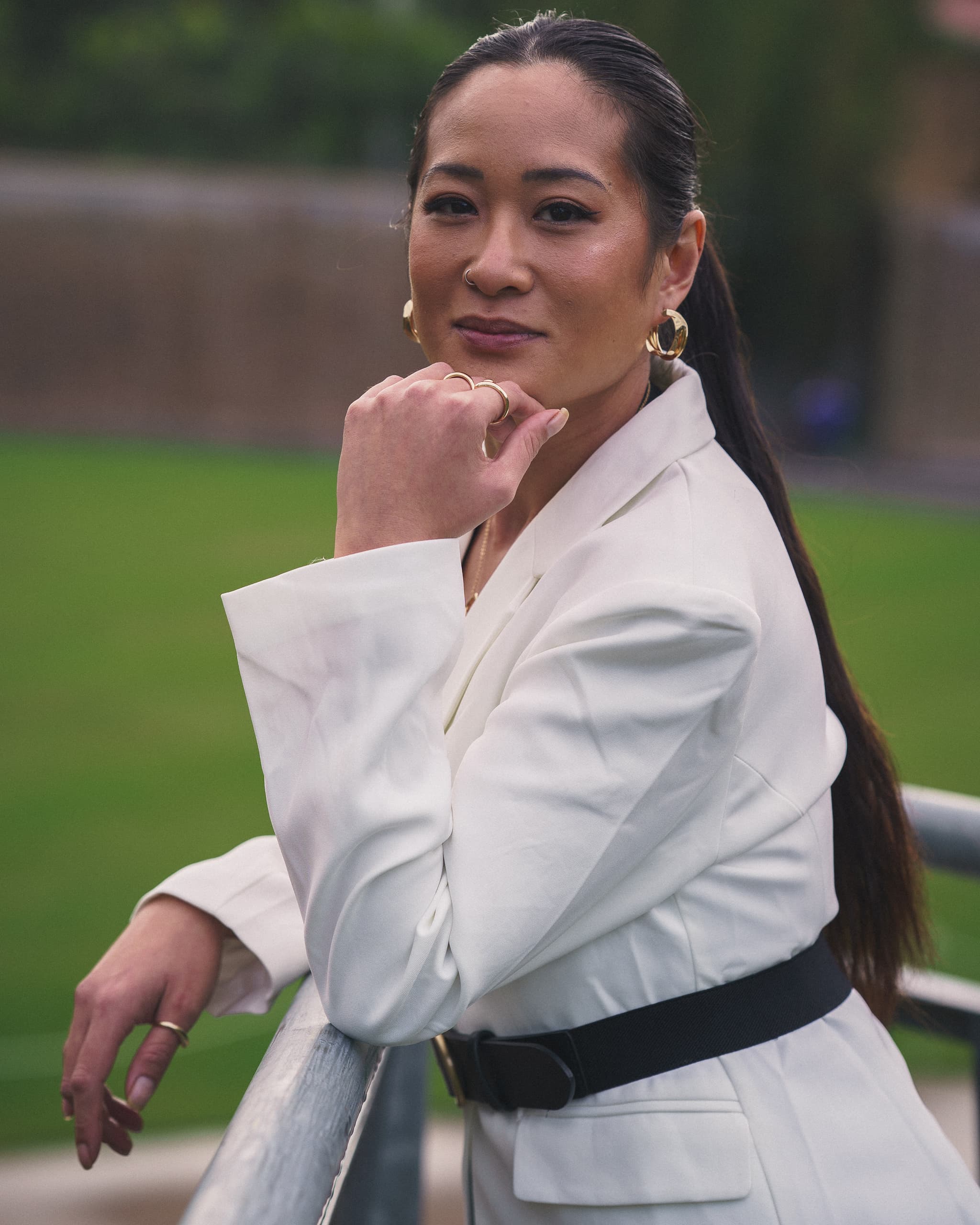 Portrait of a woman in a white blazer resting her chin on her hand at a railing